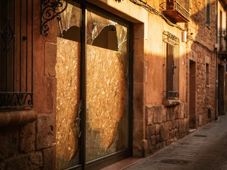 Vitrine cassée sécurisée par un panneau de bois dans une rue de village